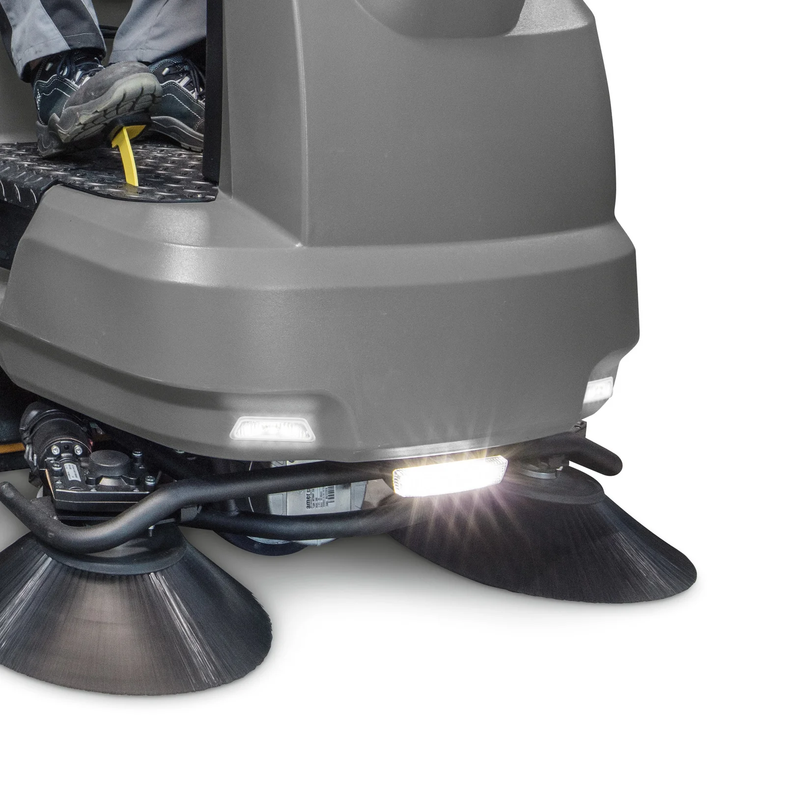 Kärcher Kehrmaschine mit zwei rotierenden Bürsten und leuchtendem Frontlicht, Fahrerfüße auf Pedalen.