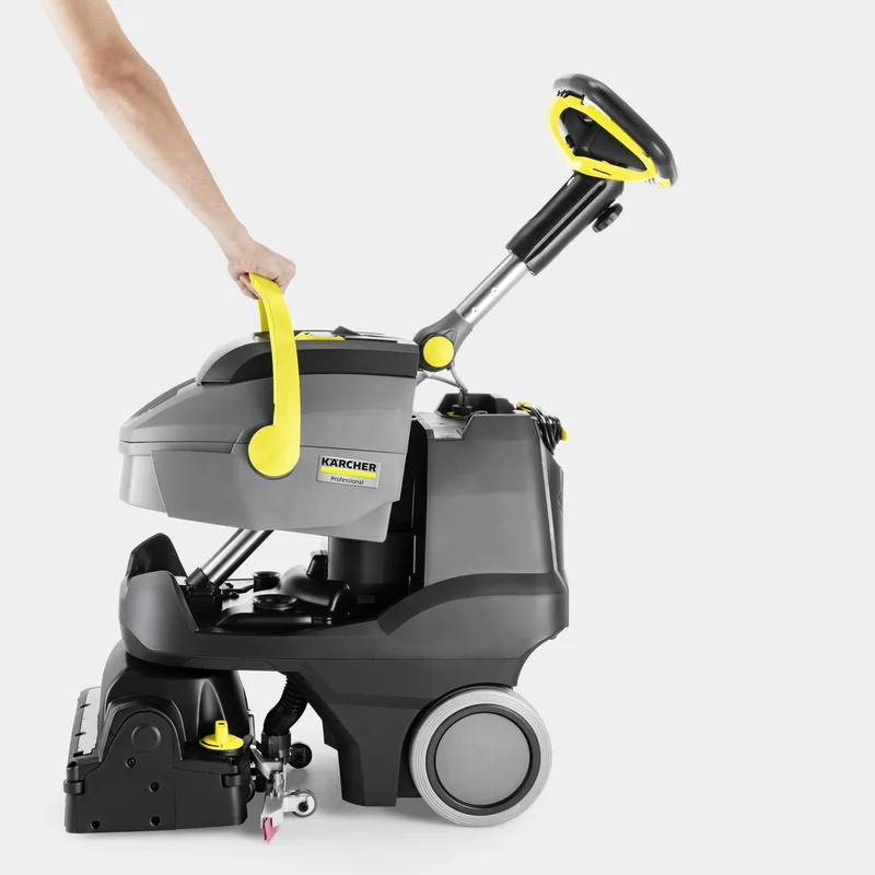 Kärcher Bodenreinigungsmaschine mit gelbem Griff, seitlich gezeigt. Eine Hand hält den Griff.