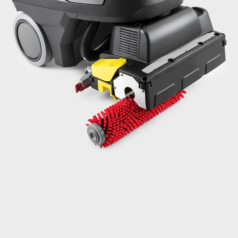 Kärcher Bodenreinigungsmaschine mit roter Bürstenwalze und gelbem Detail auf grauem Hintergrund.
