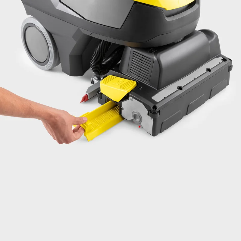Hand zieht gelbe Reinigungsbürste aus einer Kärcher Bodenreinigungsmaschine heraus.