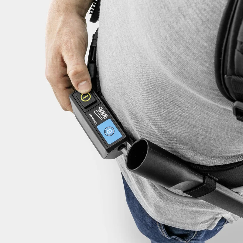 Hand hält Steuerung eines Kärcher Rucksacksaugers, graues T-Shirt und Jeans sichtbar.