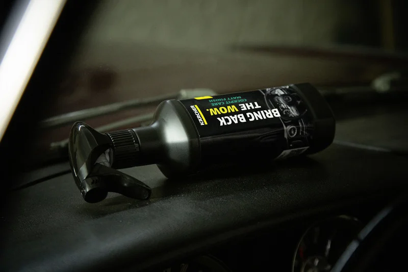 Kärcher Autopflege-Sprayflasche liegt auf einem Armaturenbrett in einem Auto.