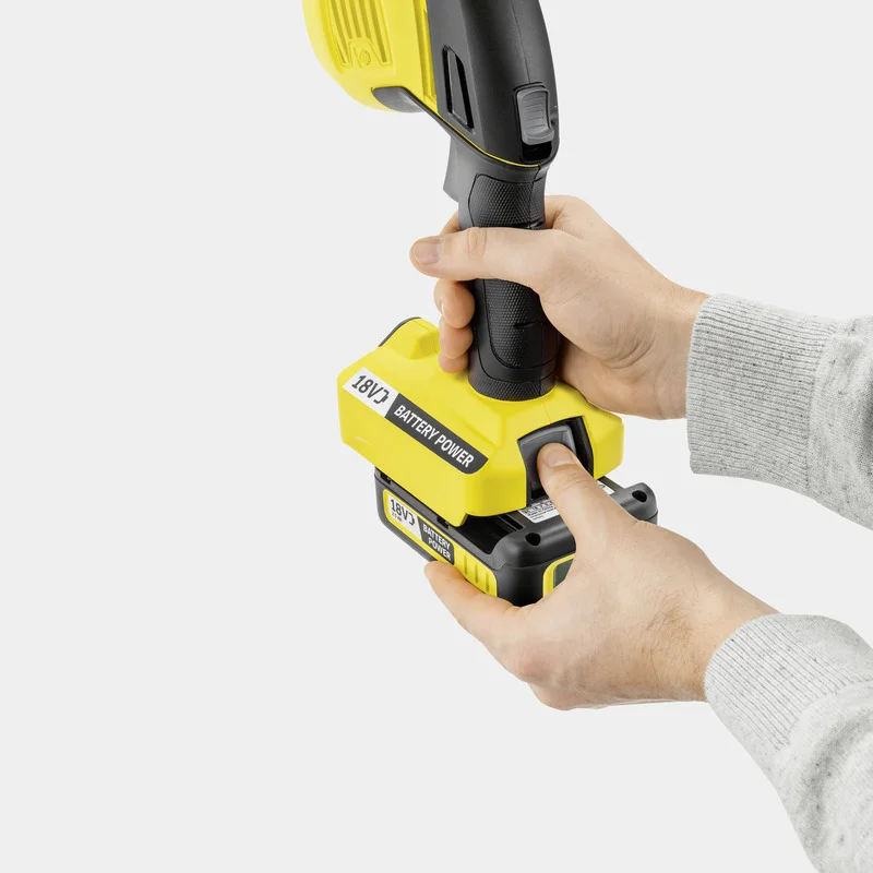 Hände setzen einen 18V Akku in ein gelbes Kärcher Gerät ein.