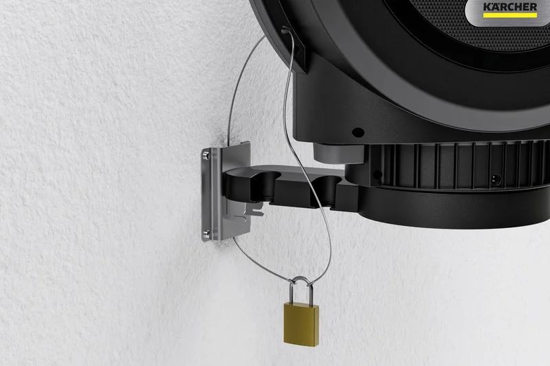 Kärcher Gerät an Wandhalterung, gesichert mit Kabel und Vorhängeschloss. Wand aus weißem Putz.