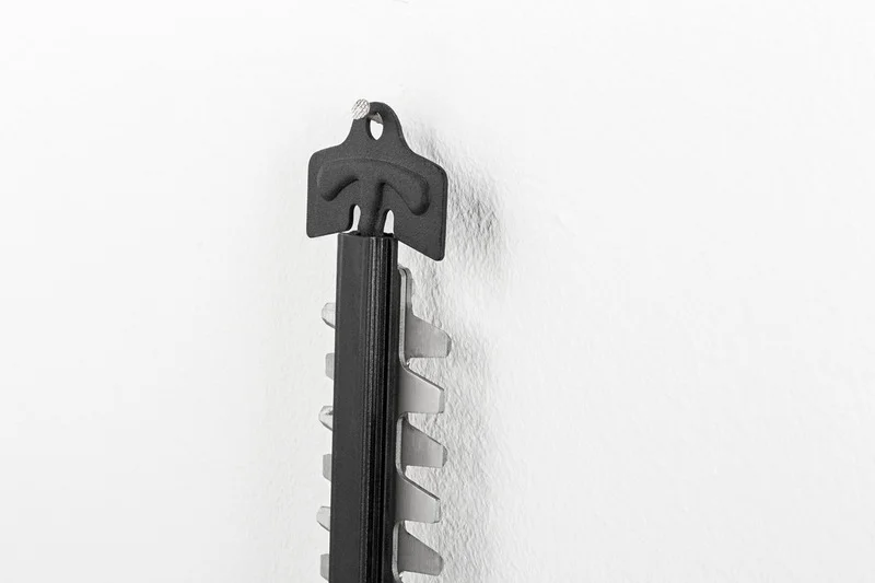 Nahaufnahme einer schwarzen Halterung mit gezackten Klingen an einer weißen Wand.