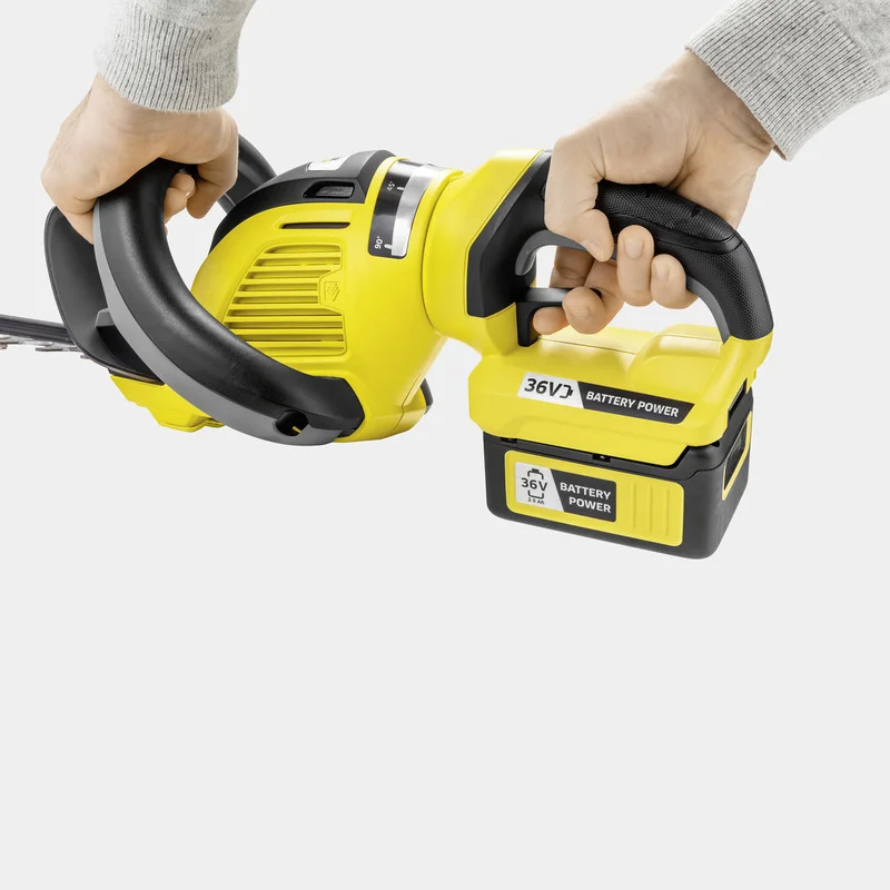Zwei Hände halten einen gelben Kärcher Akku-Heckenschere mit 36V Batterie.