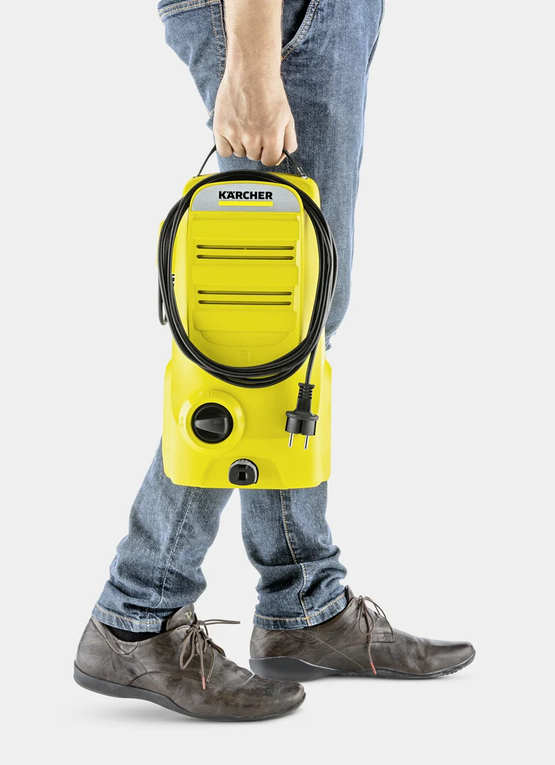 Person hält einen gelben Kärcher Hochdruckreiniger, trägt Jeans und braune Schuhe.