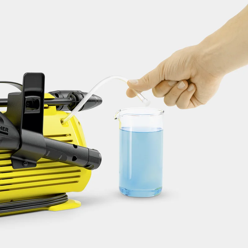 Hand hält Schlauch über Becherglas mit blauer Flüssigkeit neben Kärcher Hochdruckreiniger.