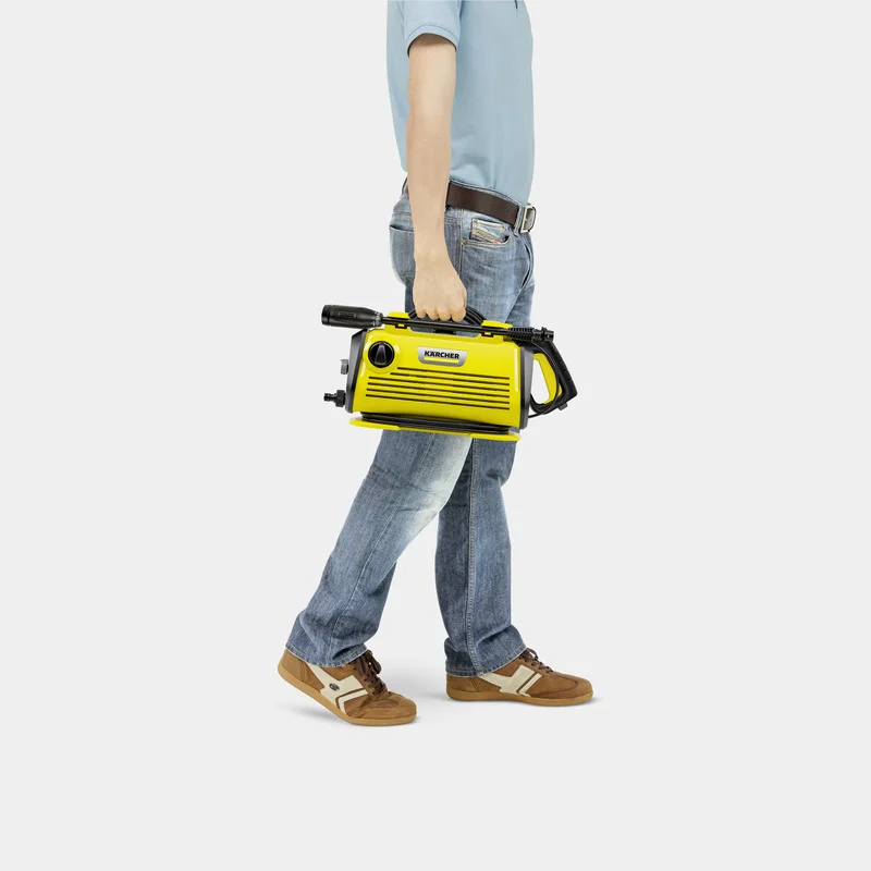 Mann in Jeans und blauem Shirt trägt einen gelben Kärcher Hochdruckreiniger in der Hand.