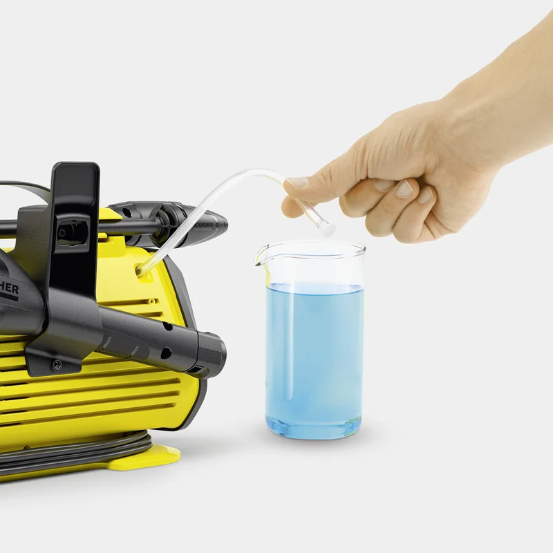 Hand hält Schlauch über Becherglas mit blauer Flüssigkeit neben gelbem Kärcher Hochdruckreiniger.