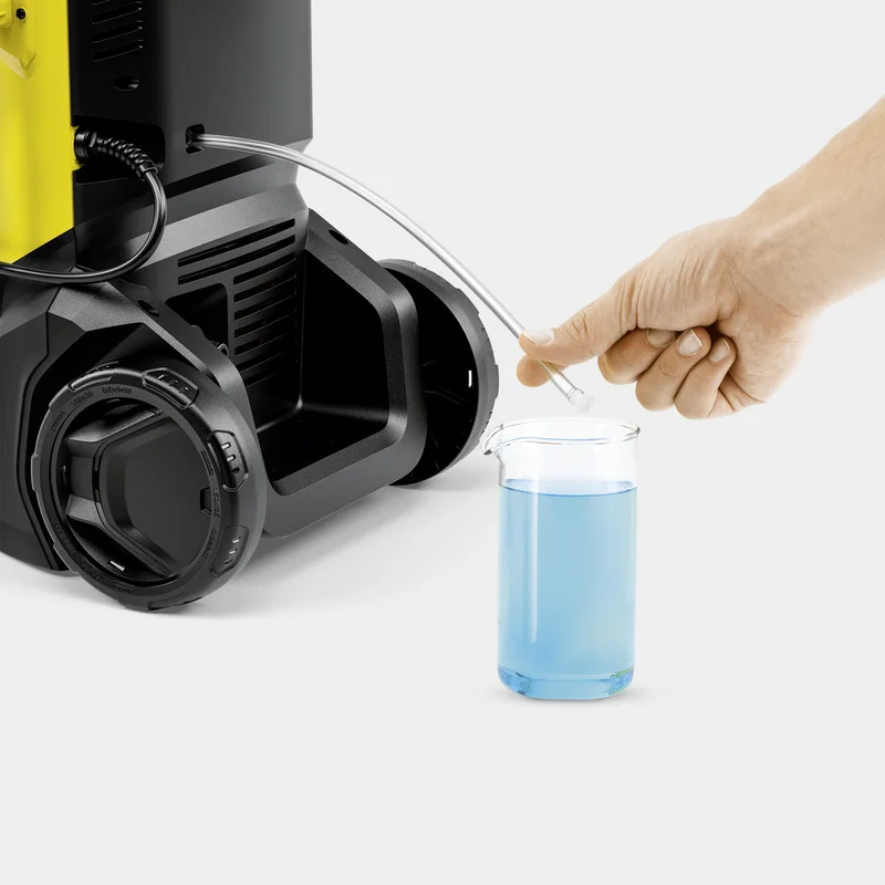 Hand führt Schlauch in Becher mit blauer Flüssigkeit, neben einem Kärcher Hochdruckreiniger.