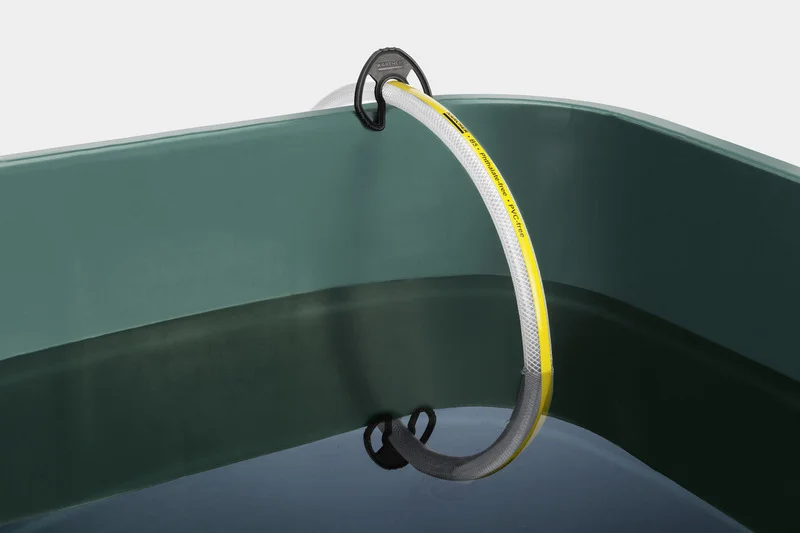Grüner Behälter mit Wasser, darin ein Kärcher Wasserschlauch mit gelbem Streifen und schwarzer Halterung.