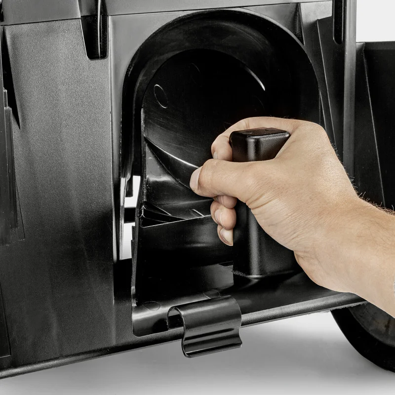 Hand greift Griff an schwarzem Gerät, möglicherweise Teil eines Kärcher Produkts. Hintergrund unscharf, Fokus auf Hand und Griff.