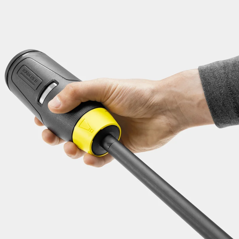 Hand hält Kärcher Hochdruckreiniger-Griff mit gelbem Anschlussstück, grauer Hintergrund.