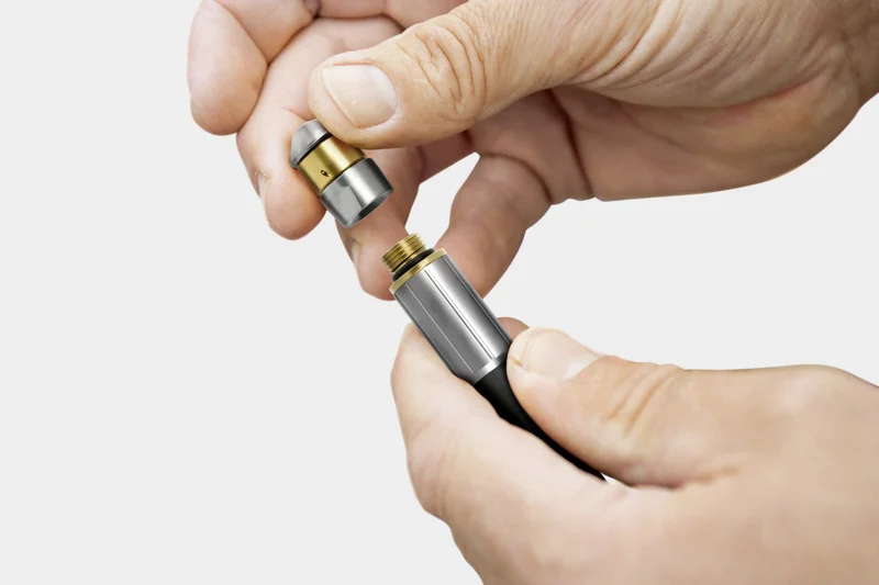 Zwei Hände halten eine Metallverbindung, die aus zwei Teilen besteht, eines davon mit einem Gewinde.