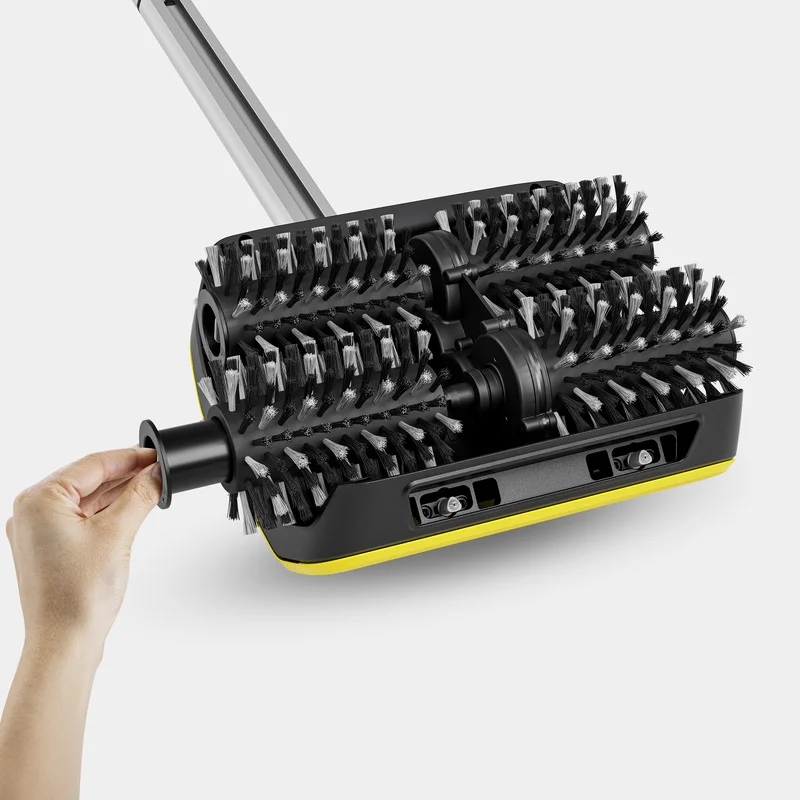 Hand zieht an einem schwarzen Griff einer Kärcher Bodenreinigungsmaschine mit rotierenden Bürsten.