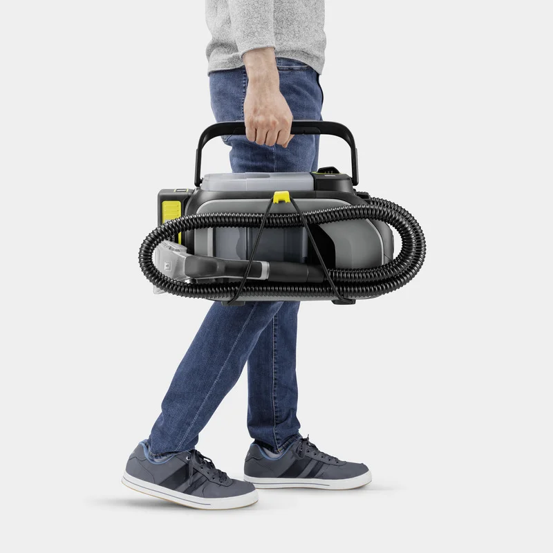 Person trägt Kärcher Dampfreiniger mit Schlauch, grauer Pullover, blaue Jeans, graue Sneakers, weißer Hintergrund.