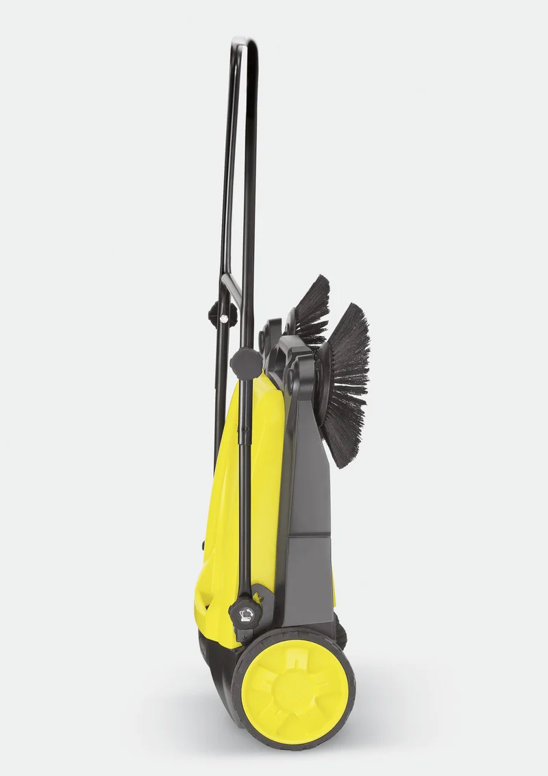 Gelber Kärcher Kehrmaschine mit zwei Rädern und Bürsten, aufrecht stehend vor grauem Hintergrund.