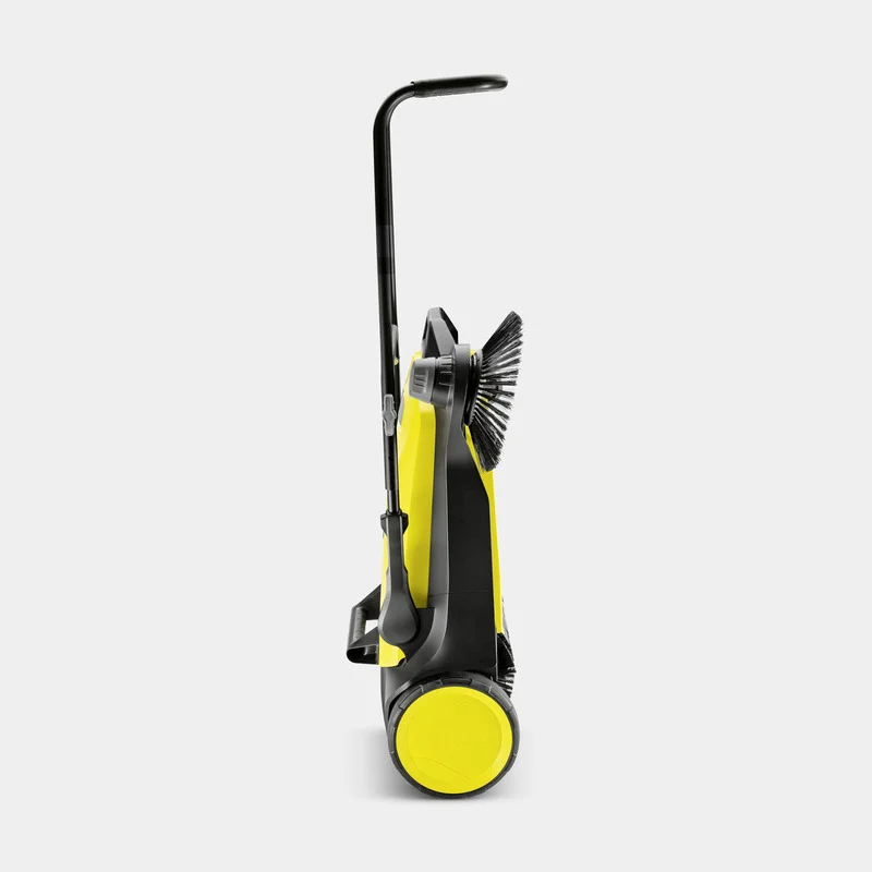 Gelber Kärcher Kehrmaschine seitlich, mit schwarzem Griff und Bürste sichtbar, auf grauem Hintergrund.