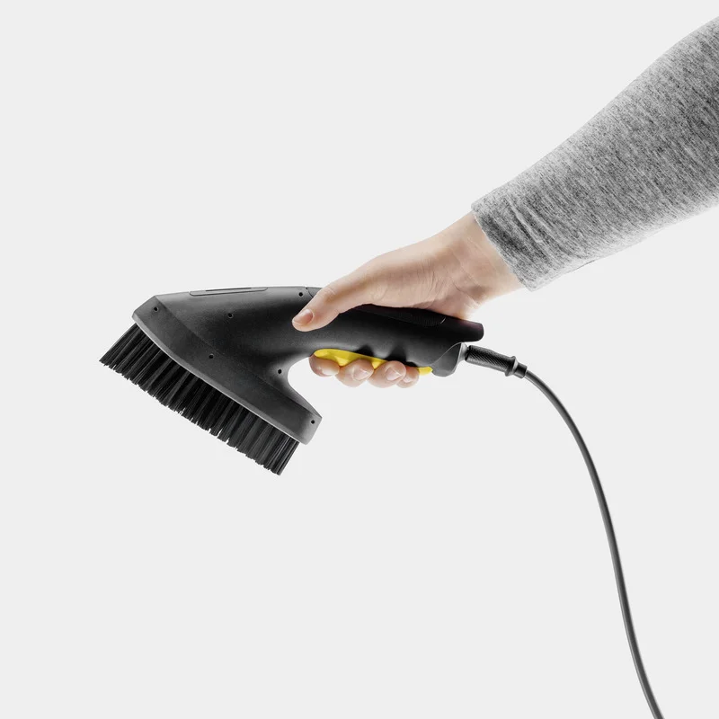 Hand hält Kärcher Dampfreiniger-Bürstenaufsatz, grauer Hintergrund.