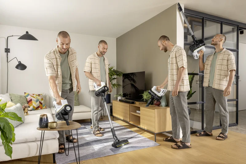 Vier Männer reinigen ein Wohnzimmer mit einem Kärcher Staubsauger. Einer saugt den Boden, ein anderer die Couch, der dritte die Wand.