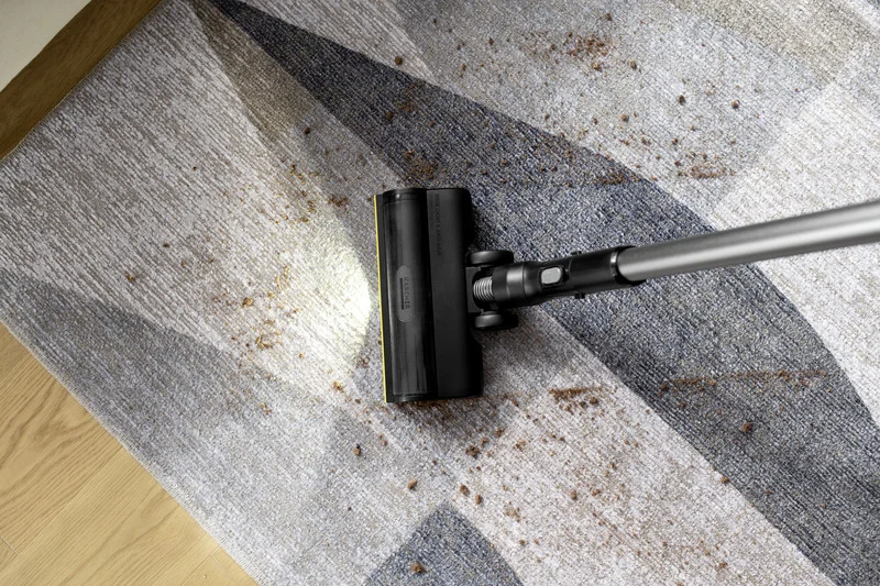 Staubsauger entfernt Schmutz von einem Teppich mit geometrischem Muster in einem Innenraum.