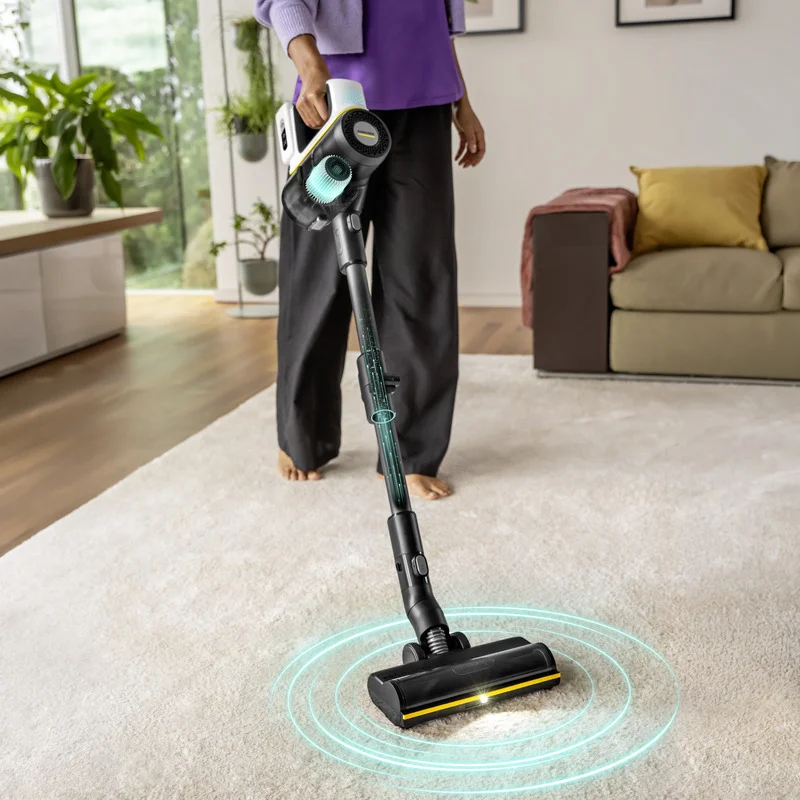 Saugen eines hellen Teppichs in einem Wohnzimmer mit einem Kärcher Akku-Staubsauger. Der Staubsauger hat eine beleuchtete Bürste und eine blaue Lichtanimation.