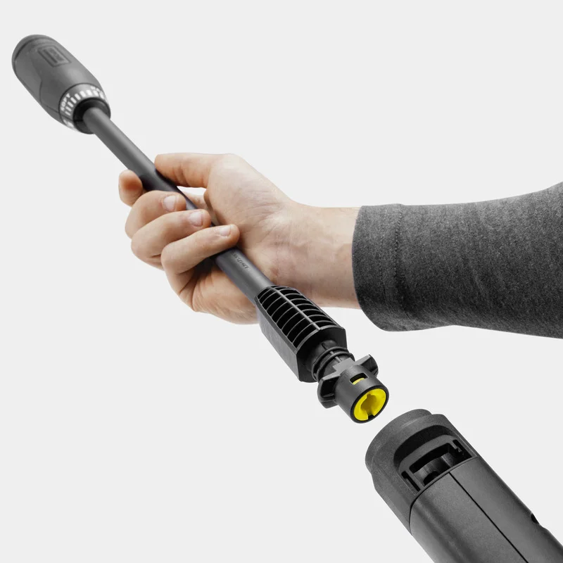 Hand connecting a Kärcher high-pressure cleaner lance to a nozzle, against a plain grey background.