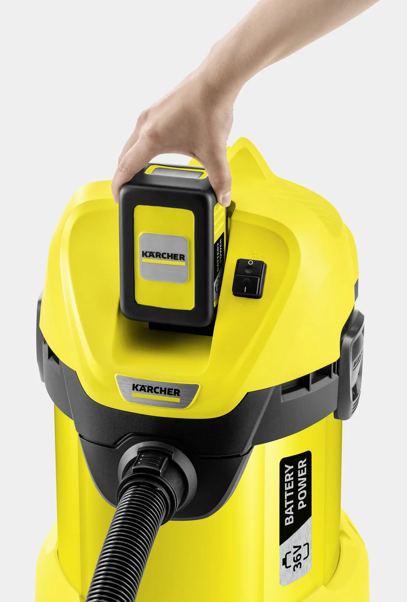 Hand setzt Akku in Kärcher Nass-Trockensauger ein. Gelbes Gerät mit schwarzem Schlauch und Batteriefach.