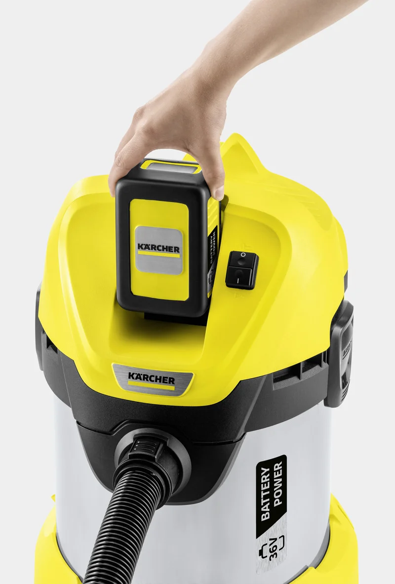 Hand setzt Akku in gelben Kärcher Nass-/Trockensauger ein. Gerät mit Batterie-Power-Label und schwarzem Schlauch.