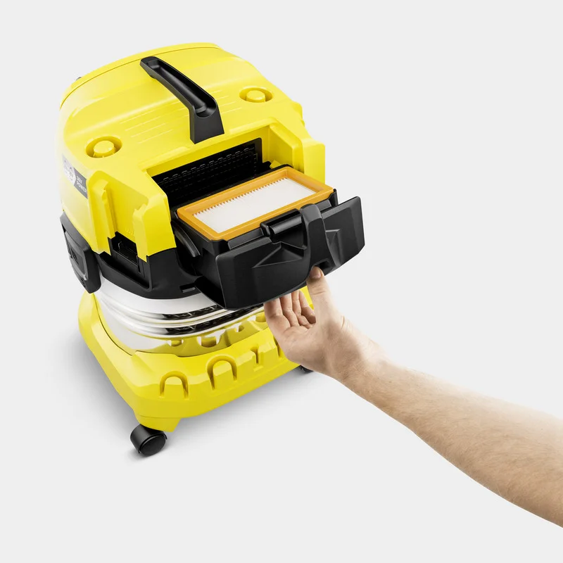 Hand öffnet Filterfach eines gelben Kärcher Staubsaugers auf weißem Hintergrund.